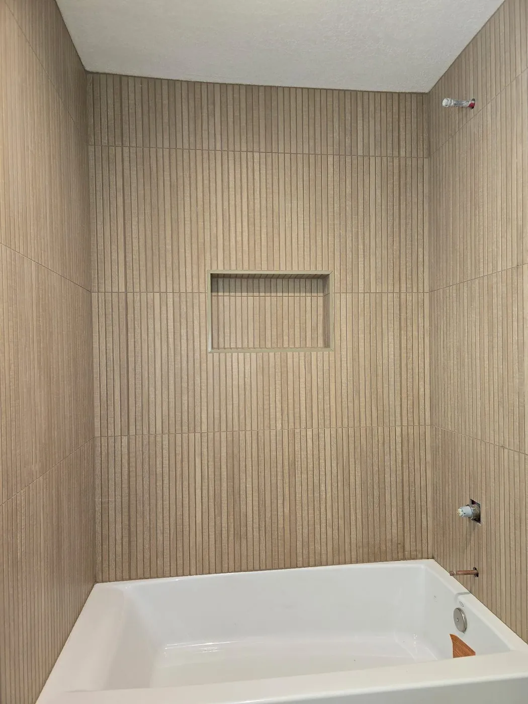 Tub surround tiled floor to ceiling with the niche centred above
