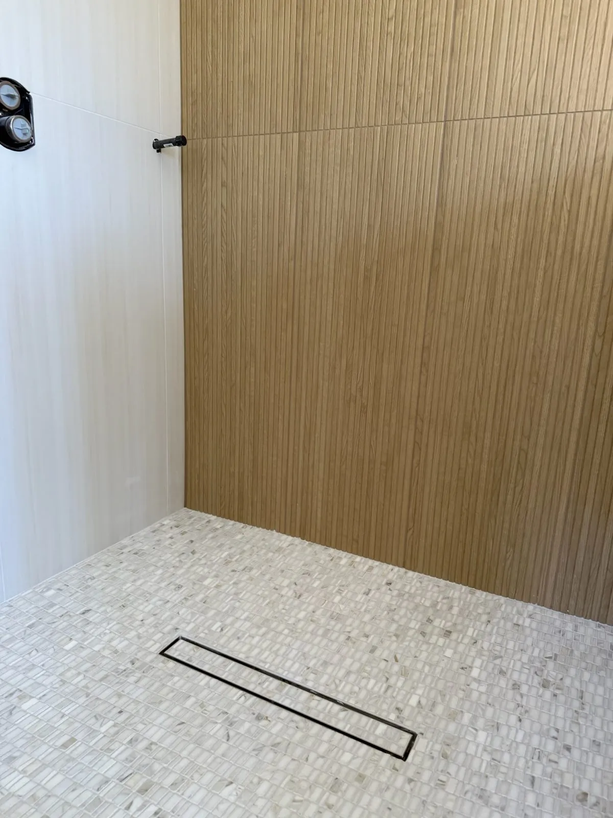Completed curbless walk-in shower with a linear drain and mosaic floor
