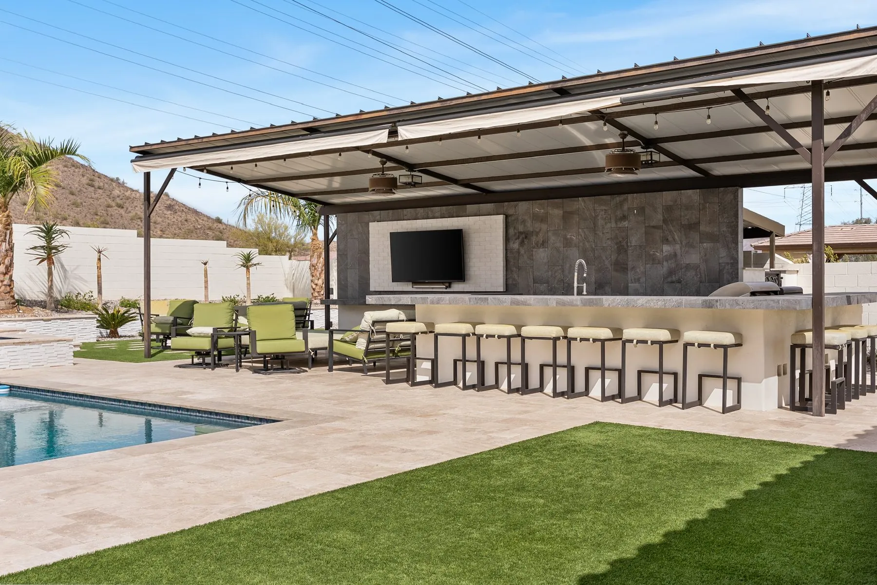 Steel ramada over a full outdoor kitchen and bar counter at the pool edge