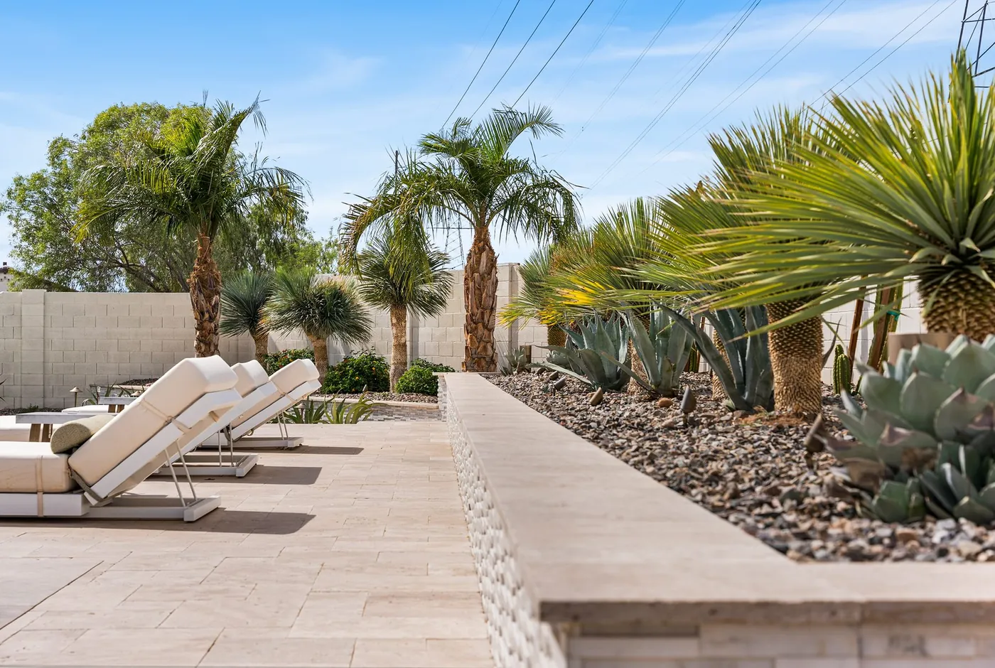Travertine pool deck with loungers and a raised planter