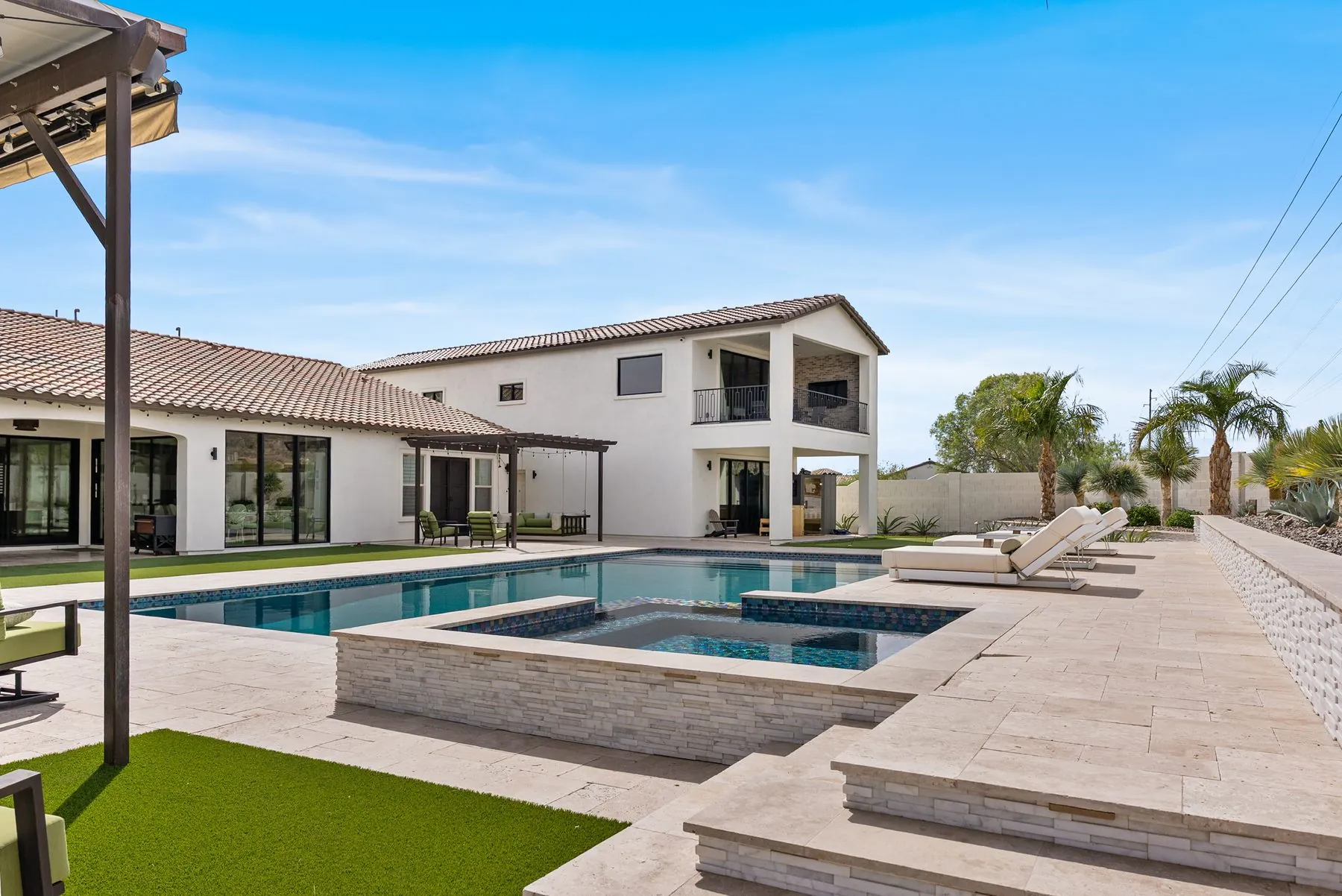 Pool and raised spa set in travertine decking, with the covered patio beyond