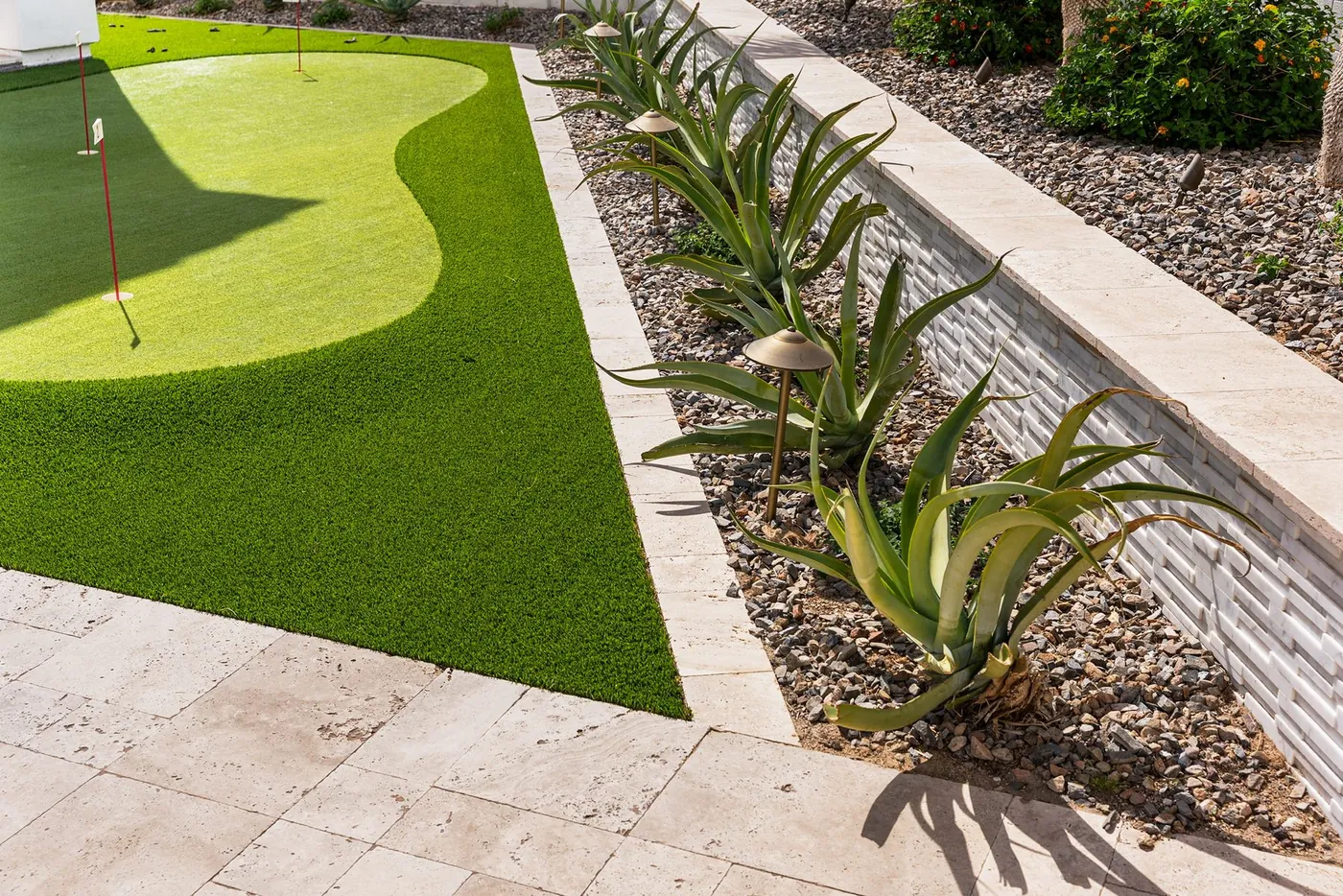 Putting green set into travertine with a stacked-stone retaining wall