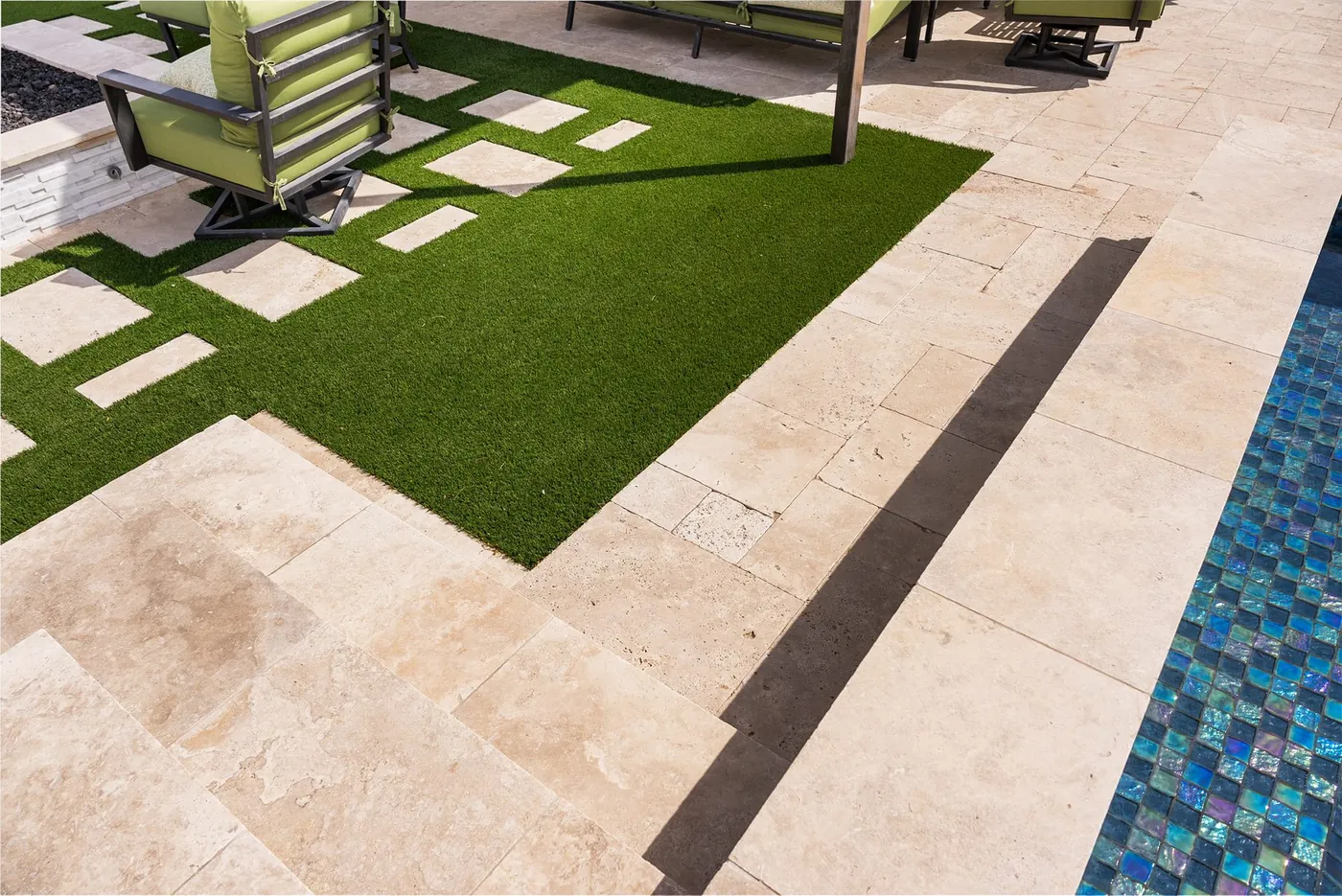 Travertine pavers set into turf, meeting the glass mosaic pool tile
