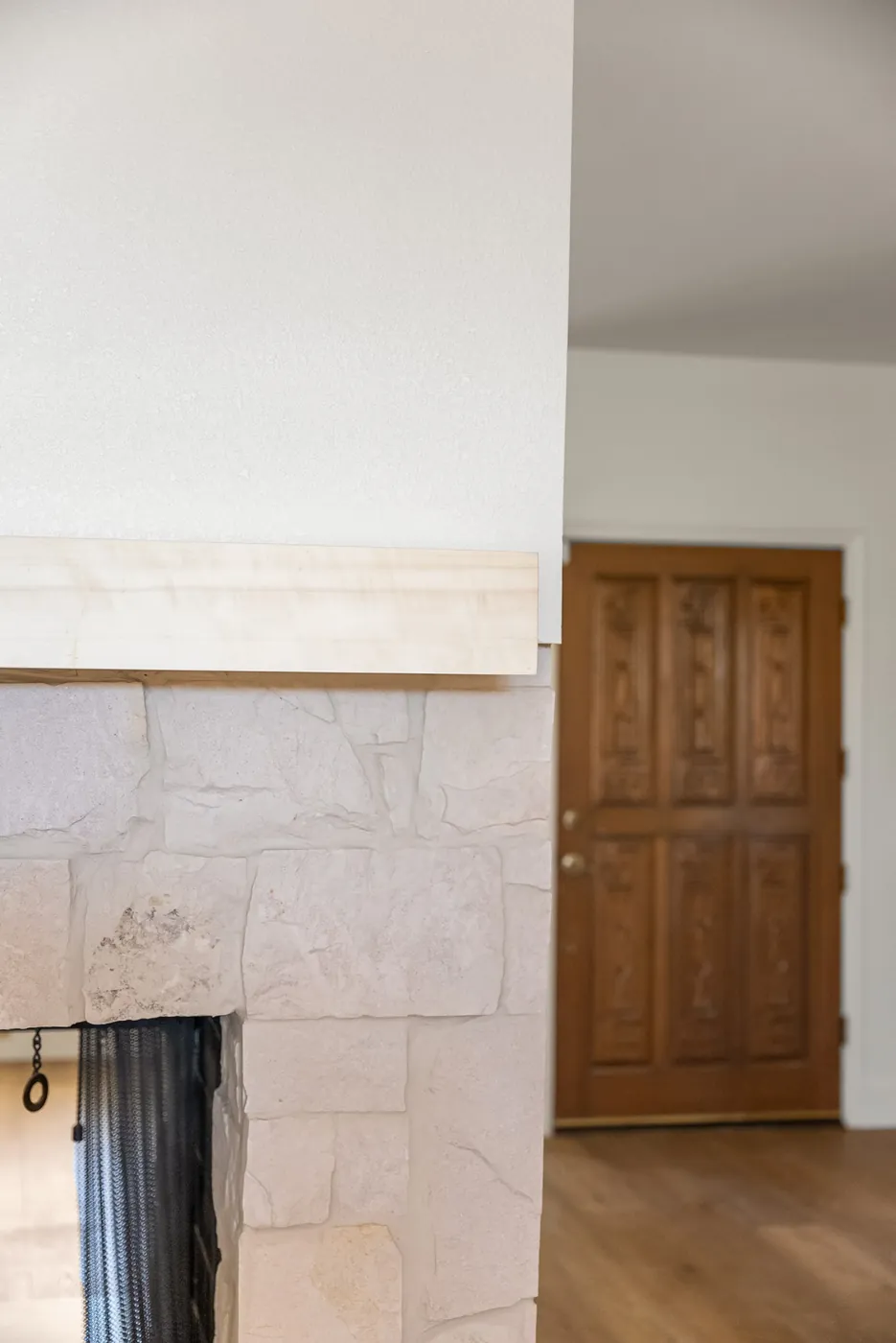 Refaced fireplace and mantel beside the panelled wood door