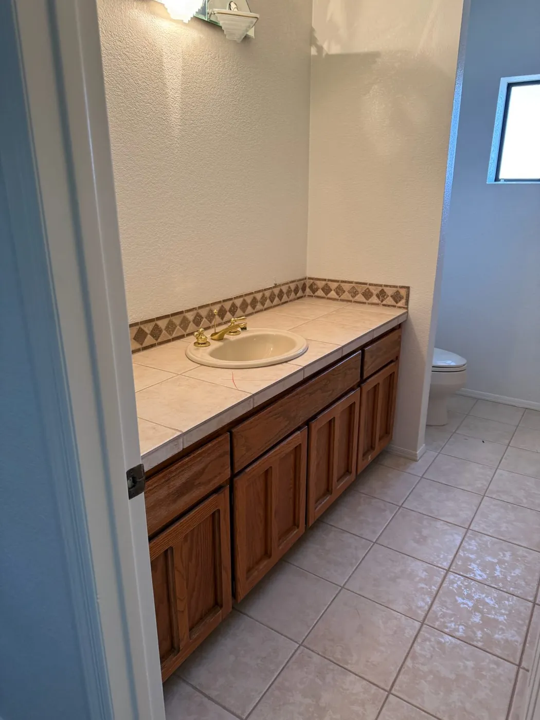 Second bathroom before renovation, with the original vanity and tiled counter