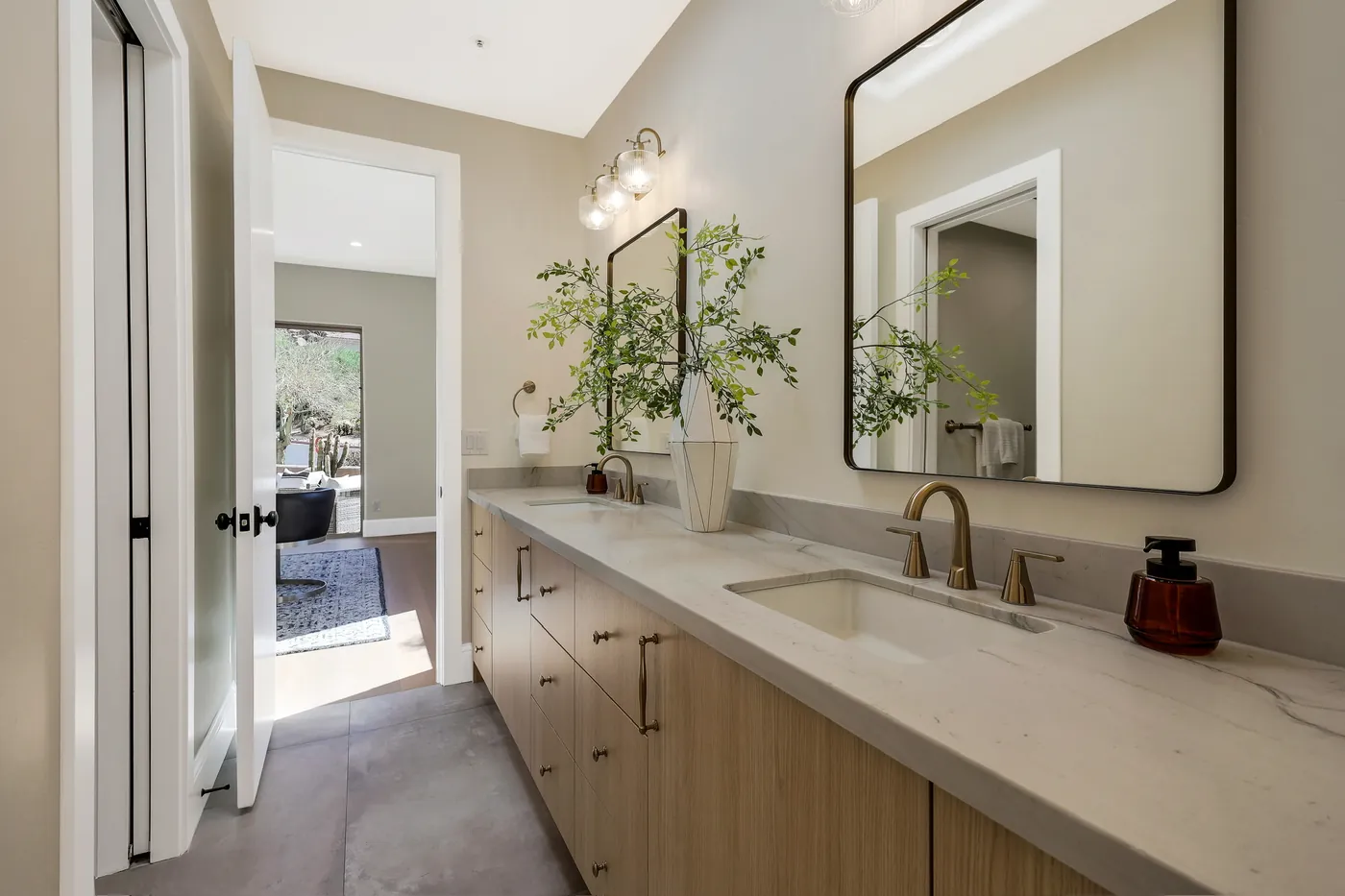 Secondary bath vanity in light wood with a black-framed mirror