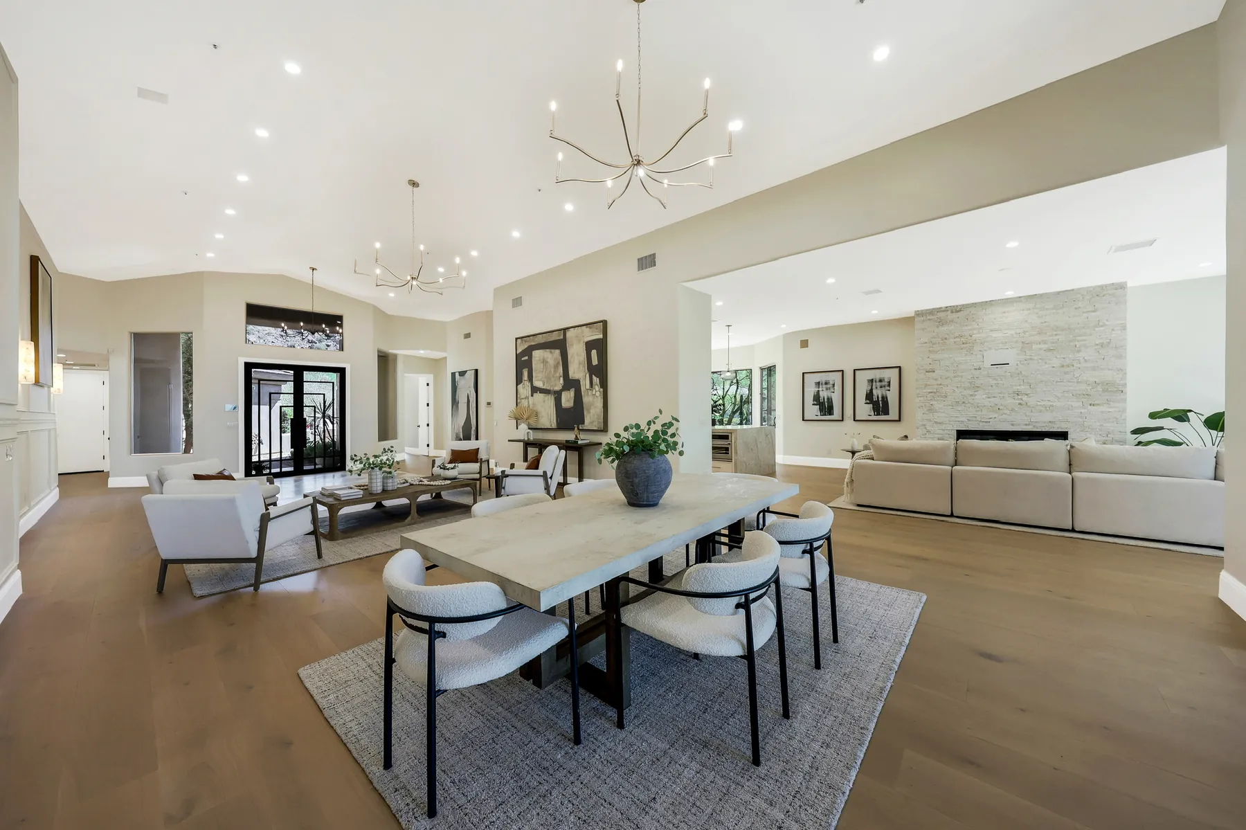 Dining table under the chandelier, with the fireplace wall and living room beyond