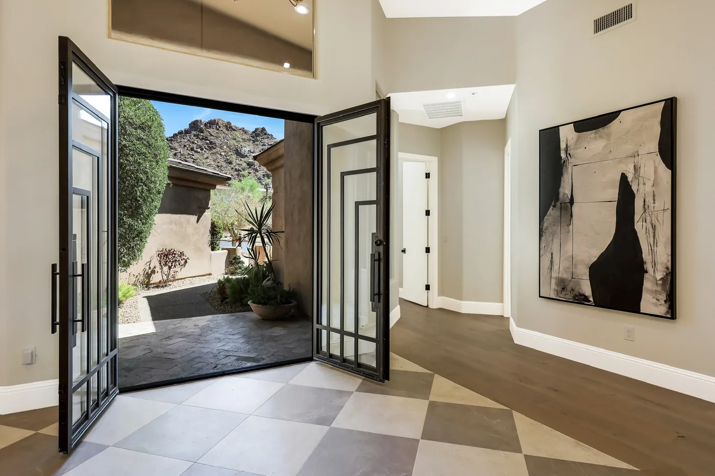 Pivot doors open to the courtyard, with the mountain behind and checkerboard tile inside