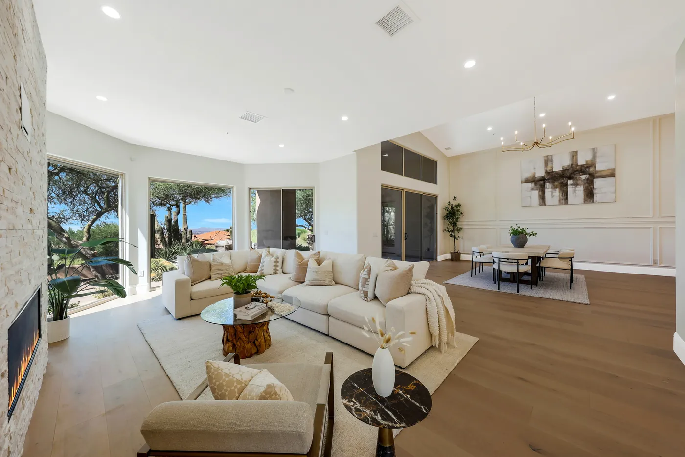 Sectional and armchairs facing the stone fireplace, with the dining area beyond