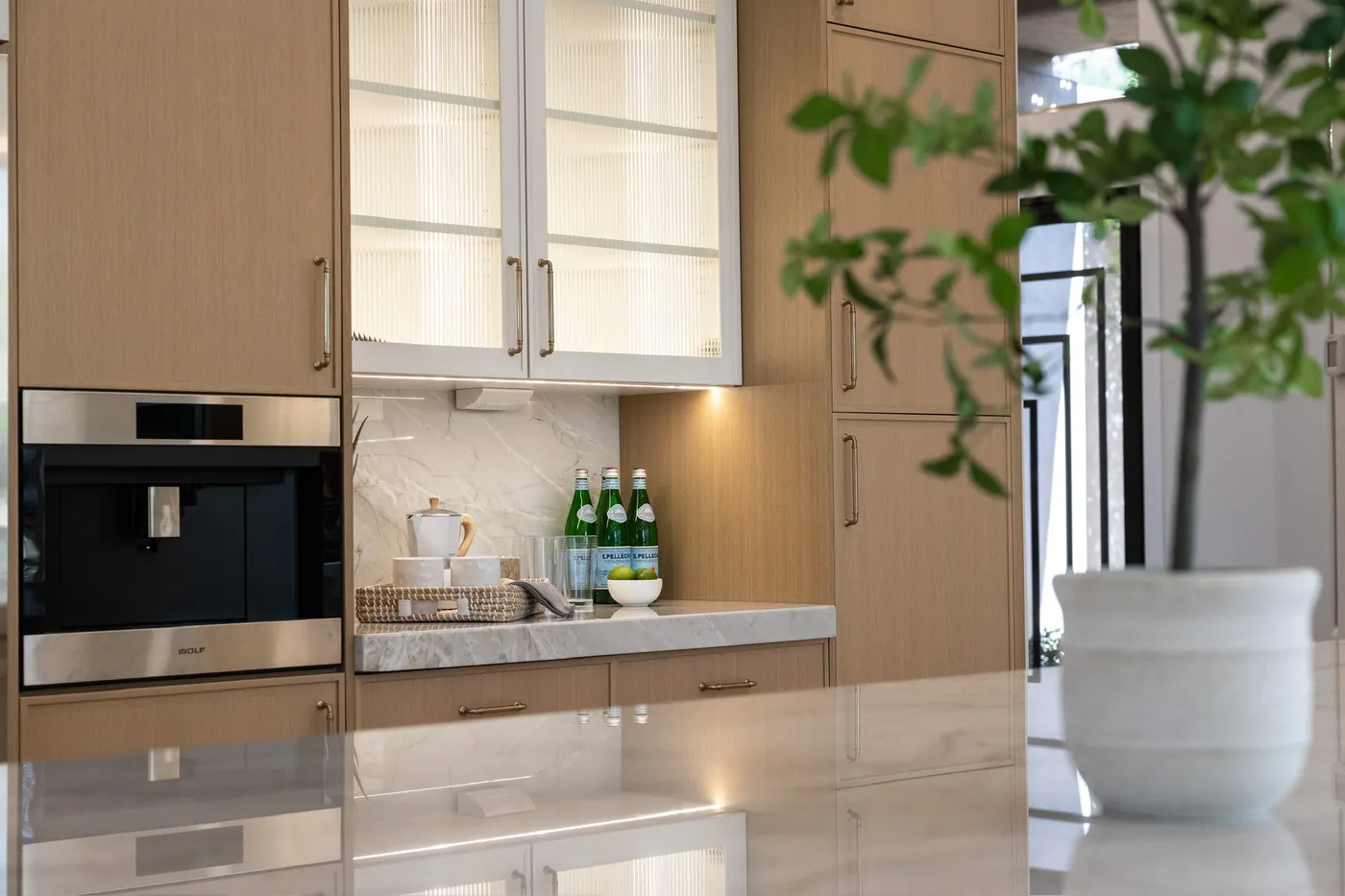 Built-in coffee station under lit glass cabinets