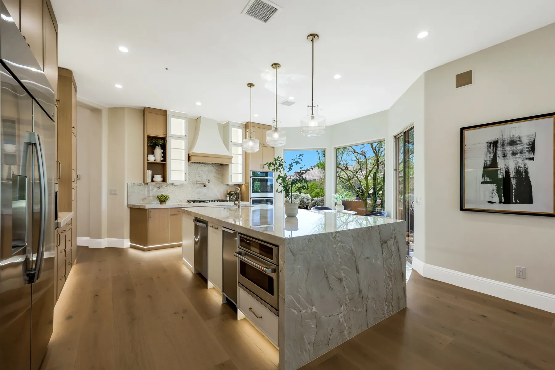 Kitchen with a veined-stone waterfall island, panelled appliances and a plaster range hood