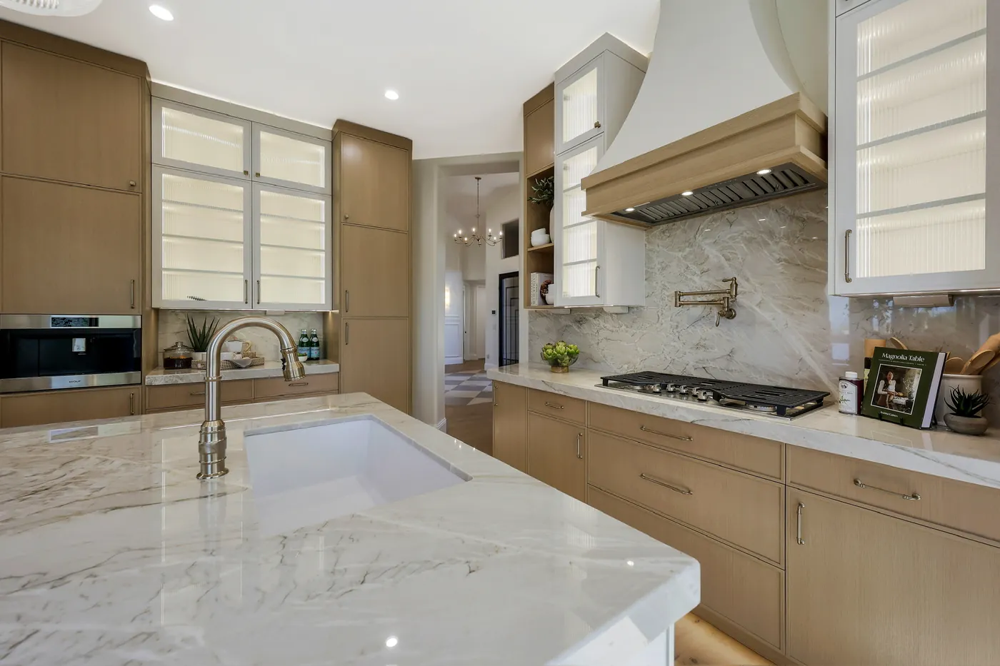 Kitchen sink run with a slab backsplash, pot filler and plaster hood