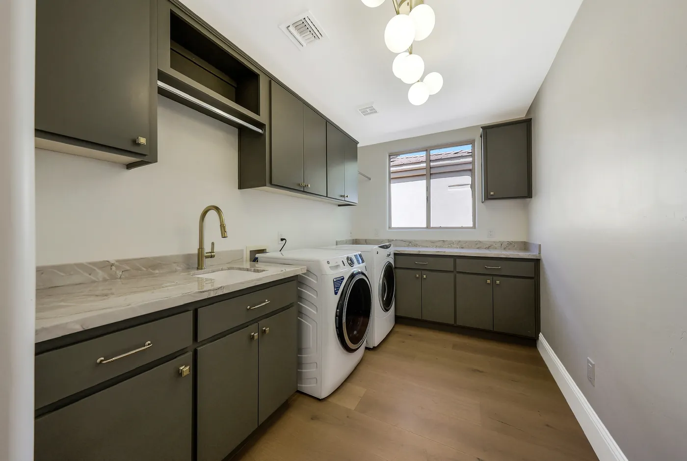 Laundry room with dark green cabinetry and a stone counter