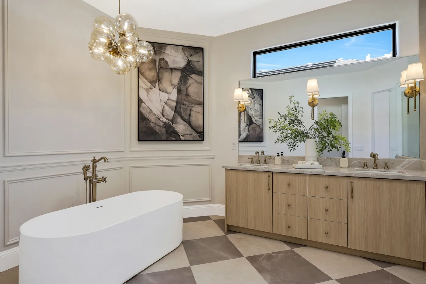 Freestanding tub beside the double vanity, under a bubble chandelier