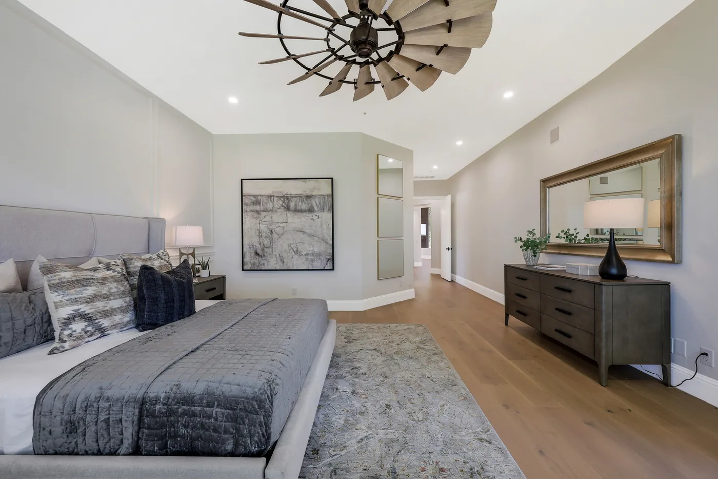Primary bedroom with a windmill ceiling fan and wide-plank flooring