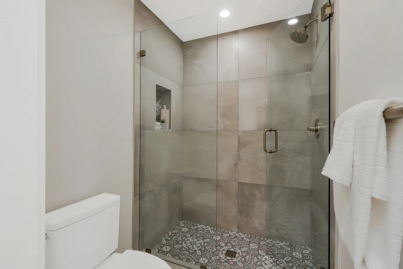 Glass-doored shower with large-format wall tile over a patterned floor