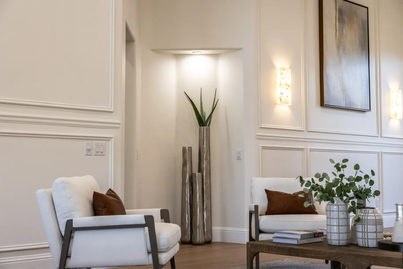 Sitting area against panelled wainscot, with wall sconces and a lit niche