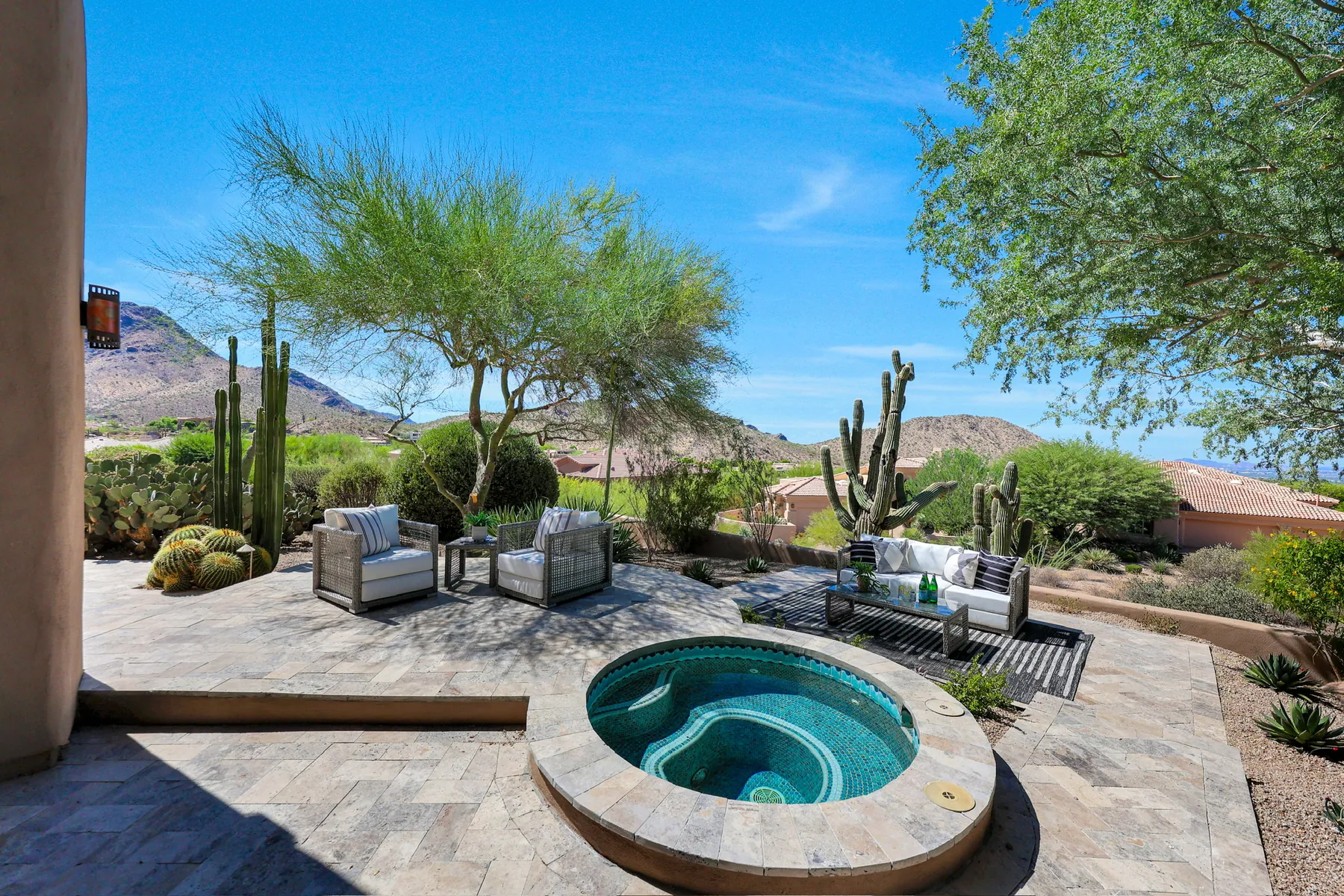 Round spa set into the paver terrace, with seating and saguaros beyond