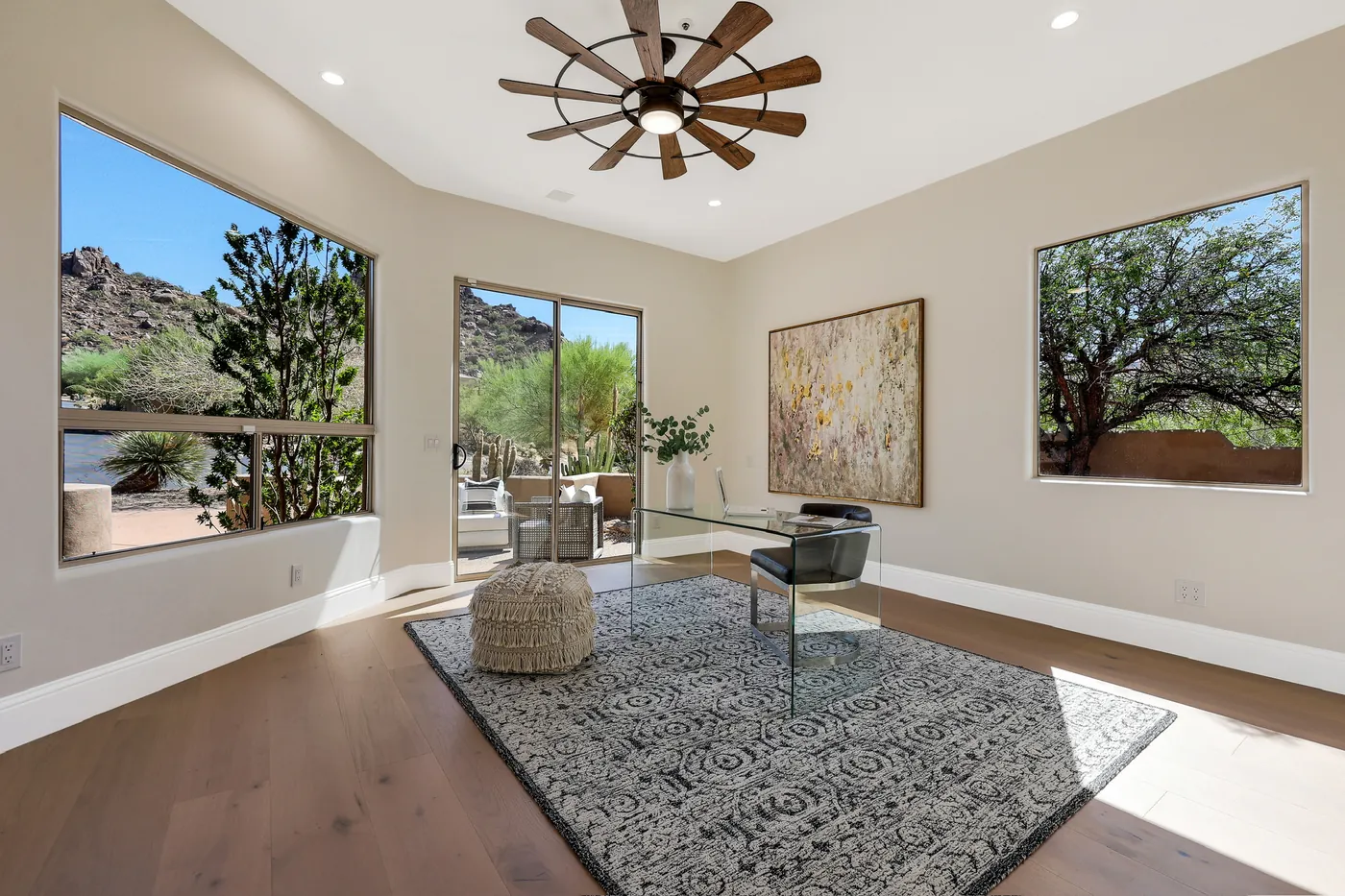 Study with a glass desk, windmill ceiling fan and windows onto the mountain