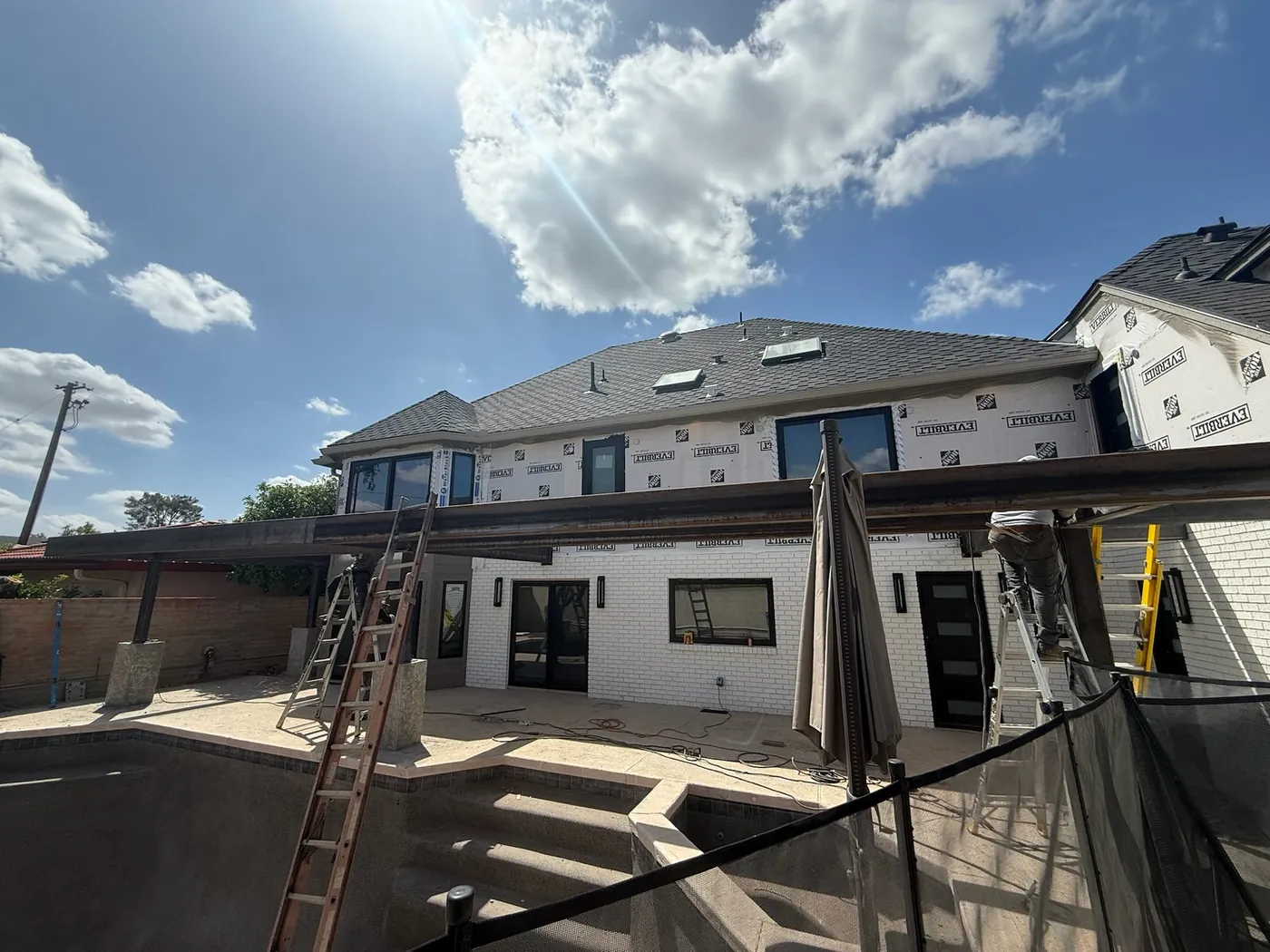 The same residence in house wrap, with windows set and the deck being formed